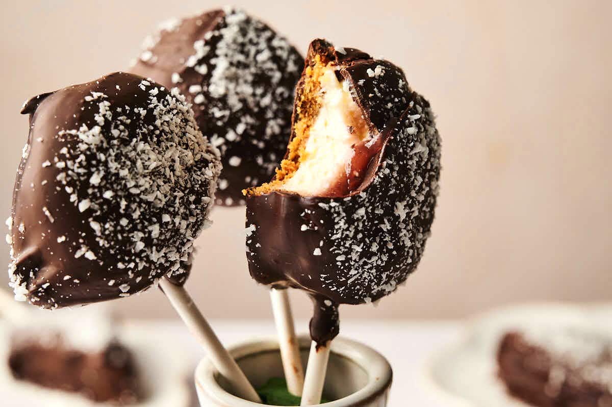 Cheesecake cake pops in stand with a bite taken out of one.