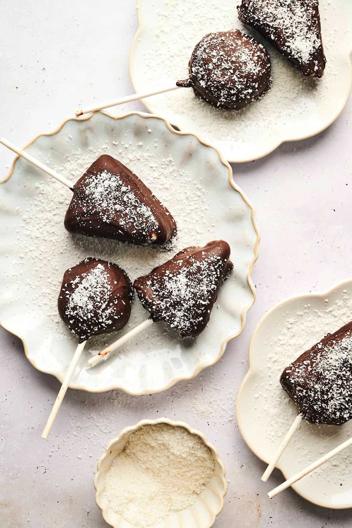 Cheesecake cake pops in different shapes on white plates.