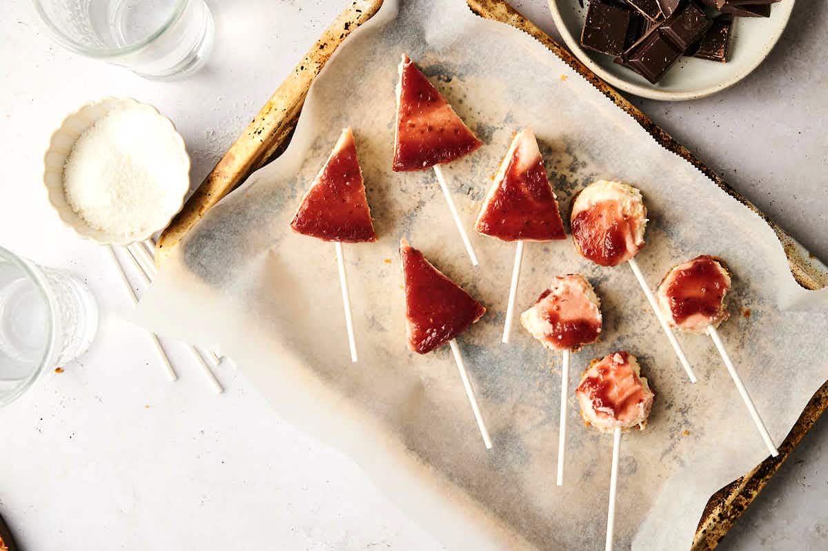 Cheesecake shaped into triangles and balls with treat sticks.
