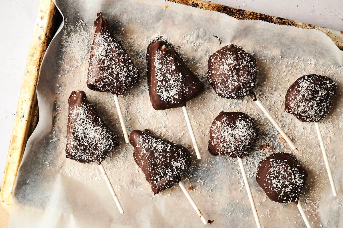 Dark chocolate covered cheesecake cake pops on parchment.