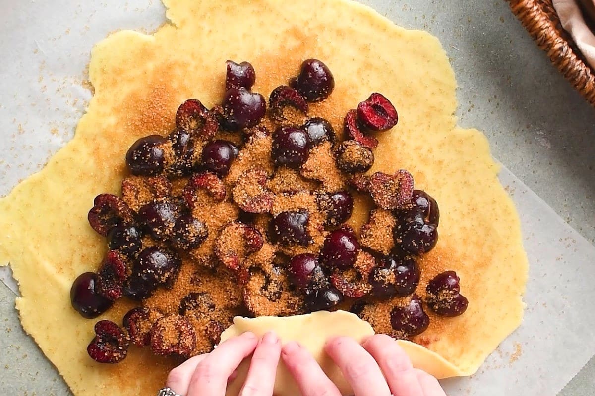 Pastry dough with cherries and brown sugar on top.