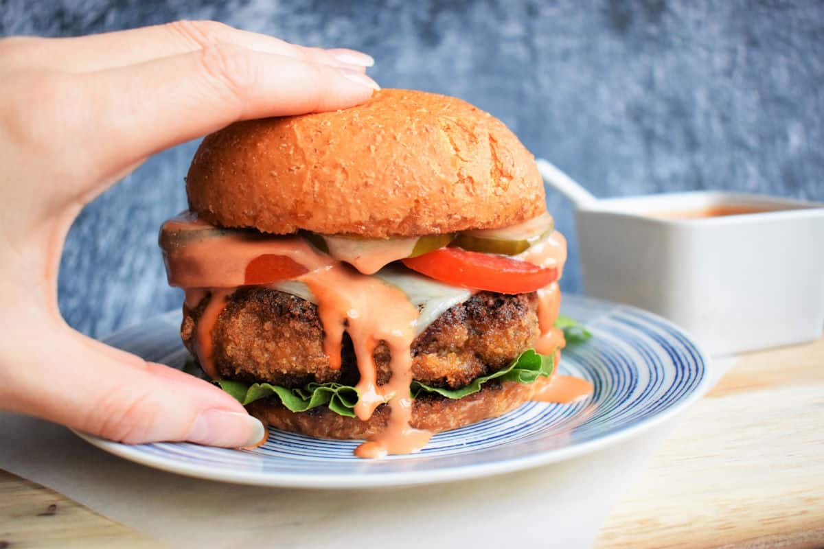 Hand holding chicken fried breaded burger.