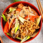 Chicken and vegetable lo mein in red bowl with chopsticks.