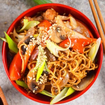Chicken and vegetable lo mein in red bowl with chopsticks.