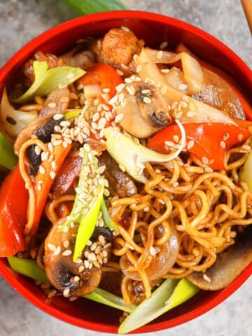 Chicken and vegetable lo mein in red bowl with chopsticks.