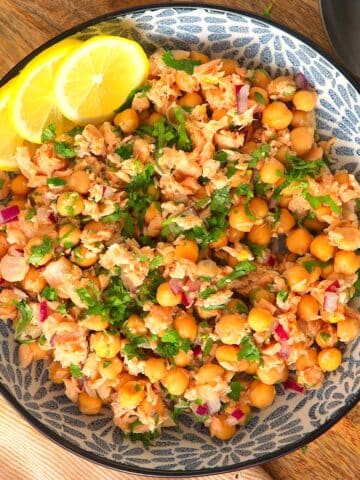 Chickpea and salmon salad in bowl with lemon slices.