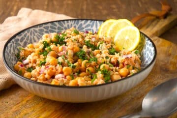 Chickpea and salmon salad in bowl with lemon slices.
