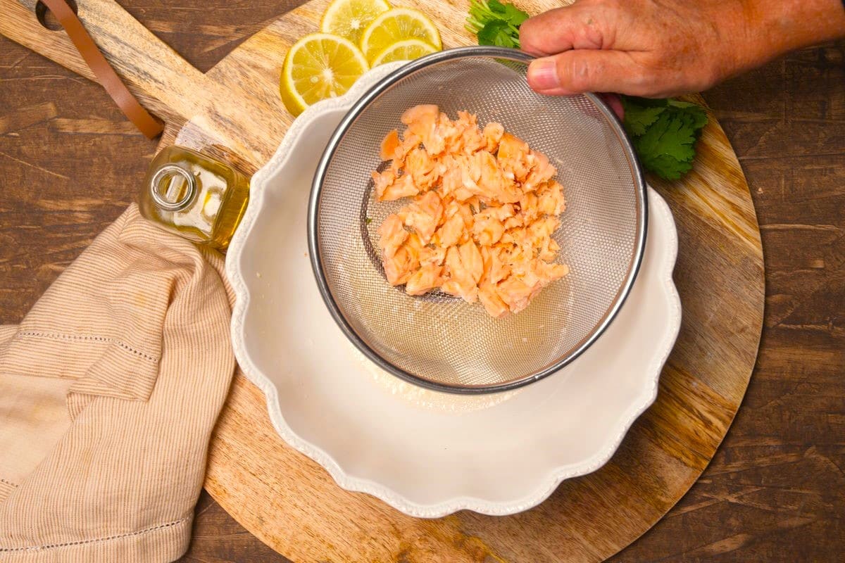 Canned salmon in mesh strainer.