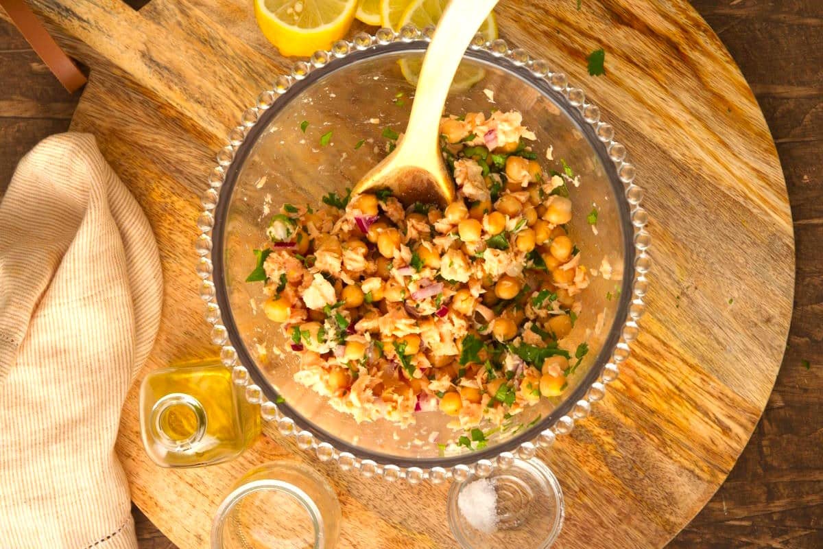 Chickpea salmon salad in bowl with wooden spoon.