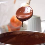 Chocolate gravy drizzling from spoon over pot.