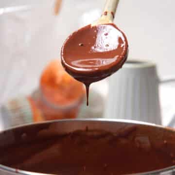 Chocolate gravy drizzling from spoon over pot.