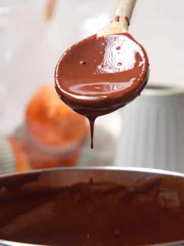 Chocolate gravy drizzling from spoon over pot.