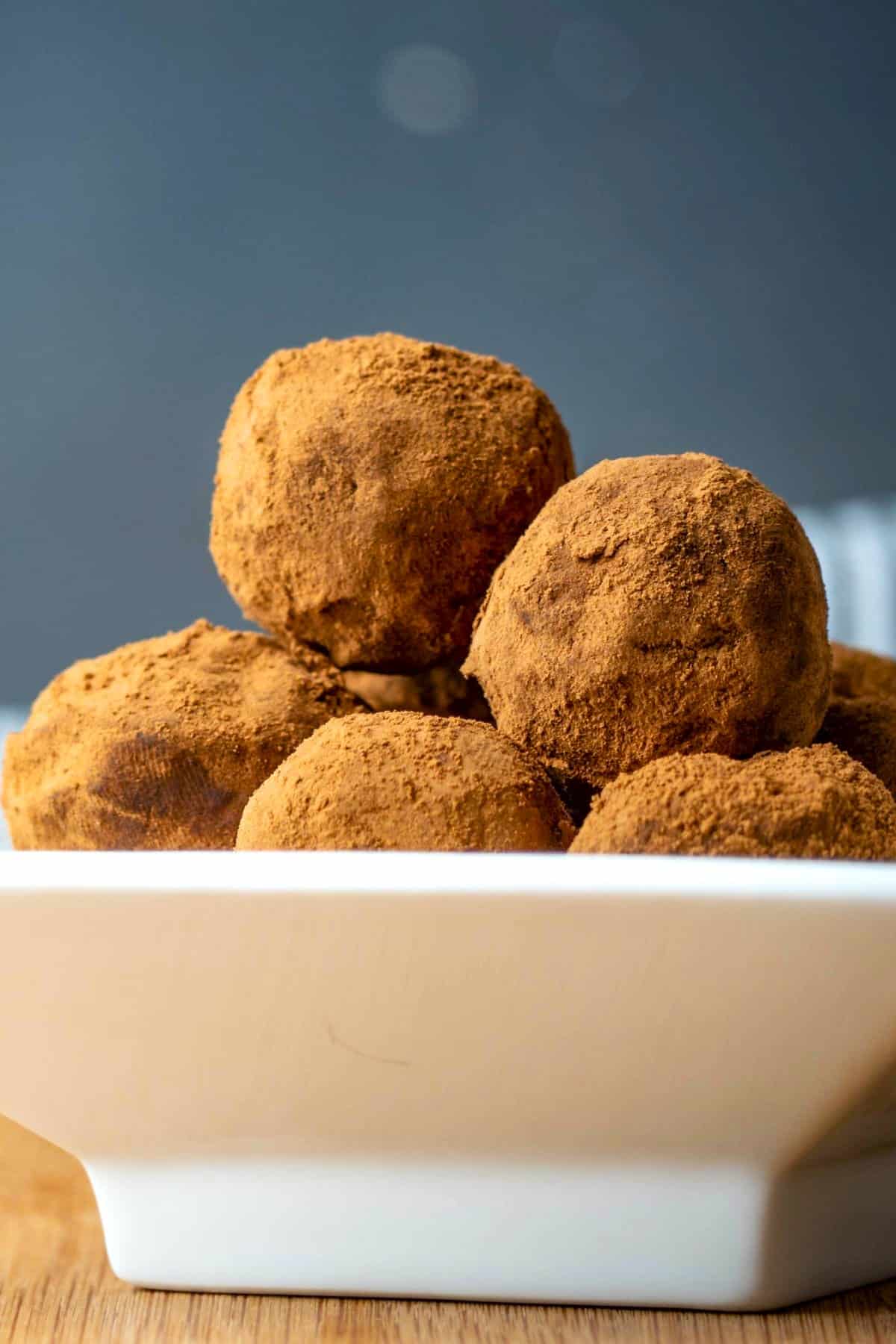 Chocolate truffles stacked on a white dish.