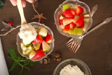 Fruit salad in clear glass bowls with forks on the side.