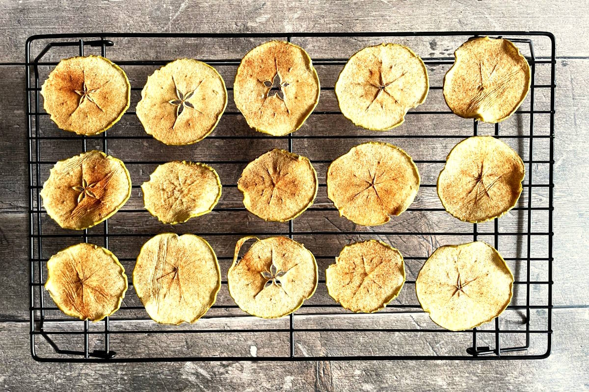 Sliced, dried apple chips on cooling rack.