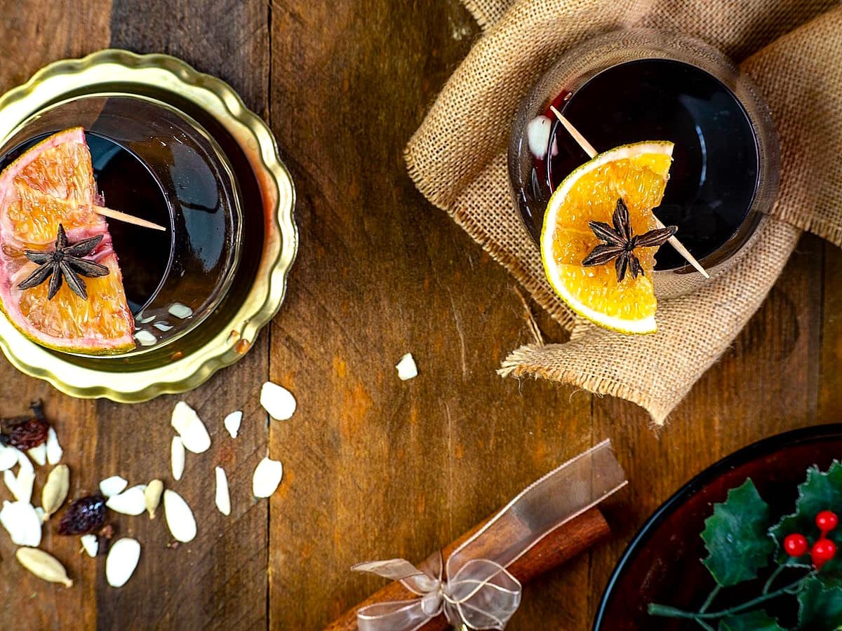Cinnamon orange glögg in wine glasses with Christmas decorations.