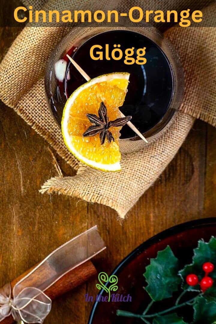 Cinnamon orange glögg in wine glass with Christmas decorations.