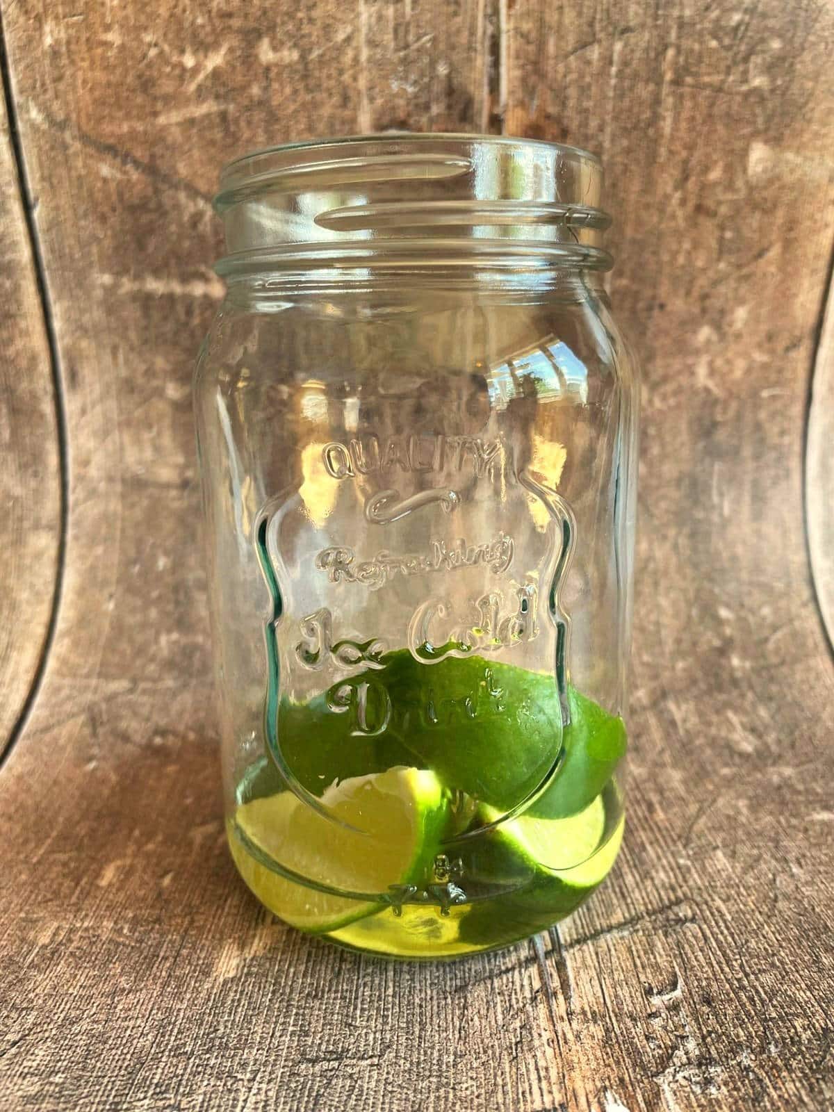 Limes and simple syrup in glass.