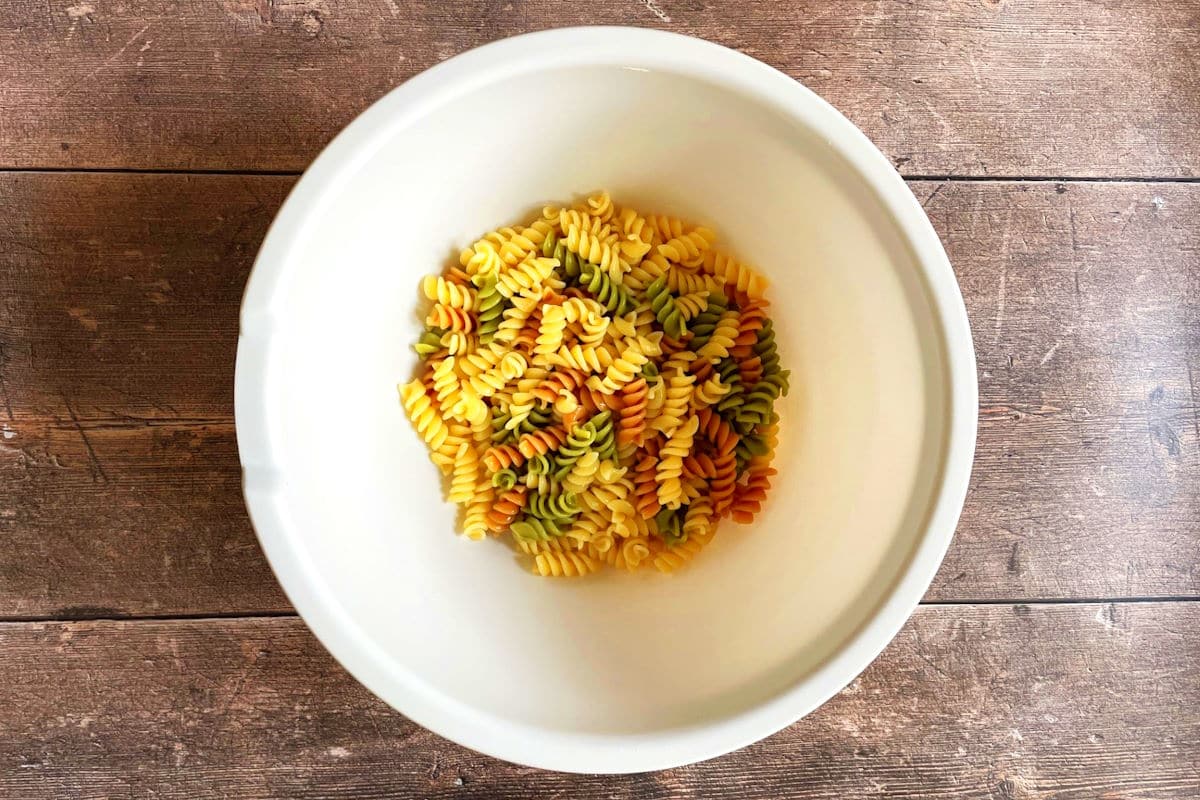 Cooked tri color spiral pasta in large bowl.