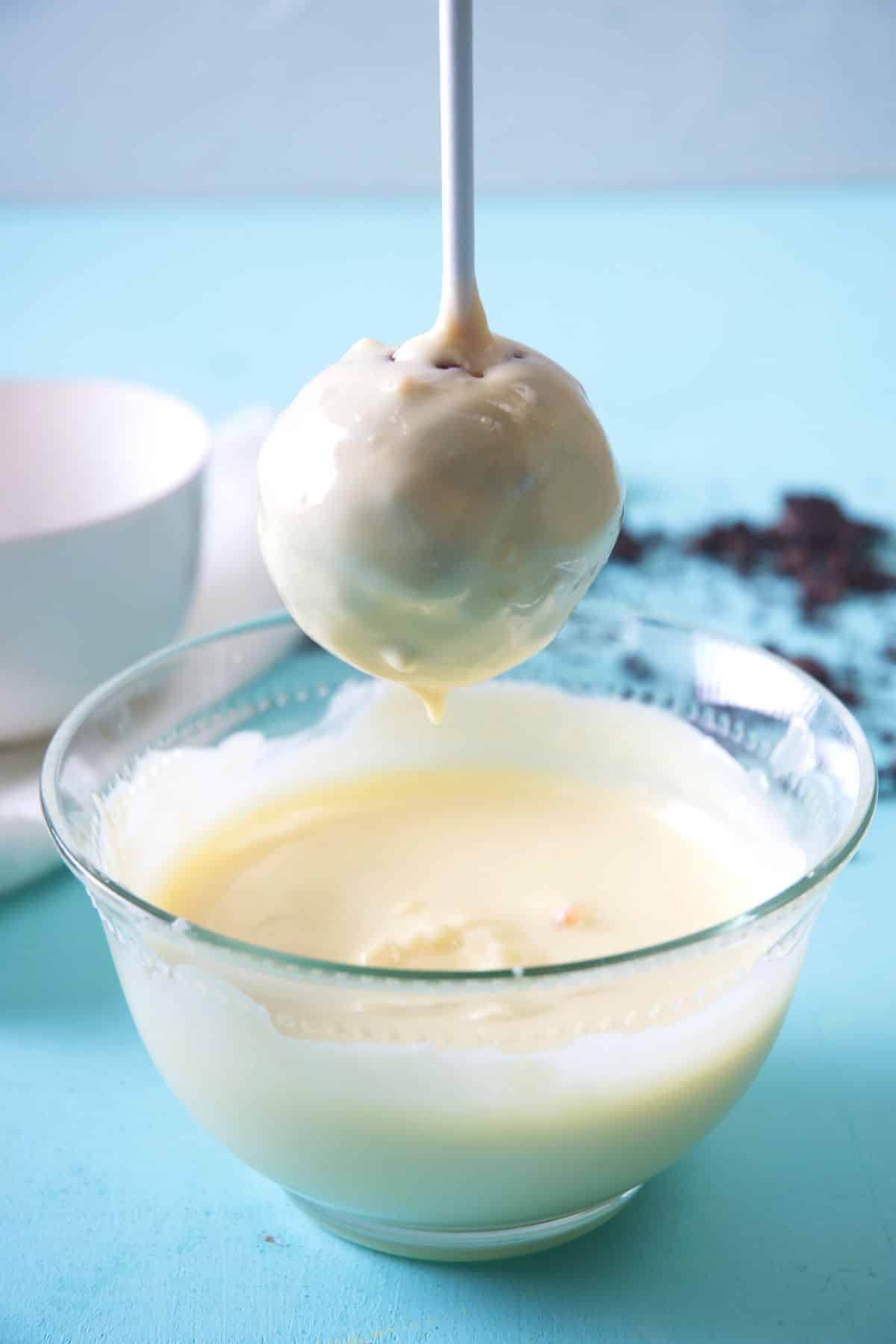 Oreo cake pop getting dipped in white candy melts.