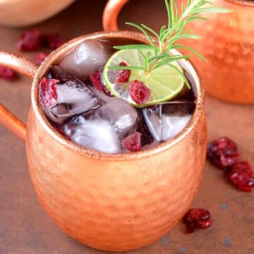 Cranberry Moscow mule in copper mug with lime garnish.