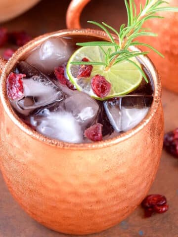 Cranberry Moscow mule in copper mug with lime garnish.