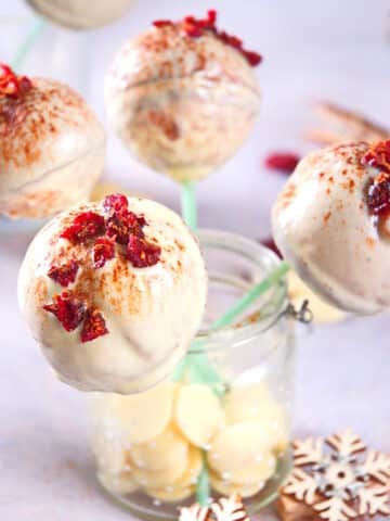 Cranberry white chocolate cake pops sprinkled with cinnamon in decorative jar.