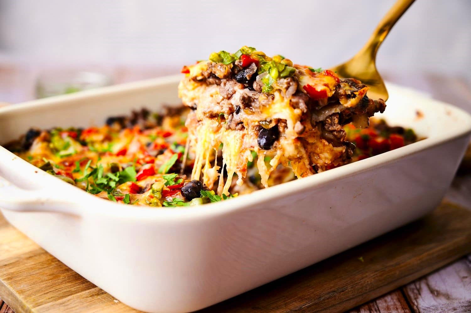 Creamy burrito casserole getting scooped up by spatula.