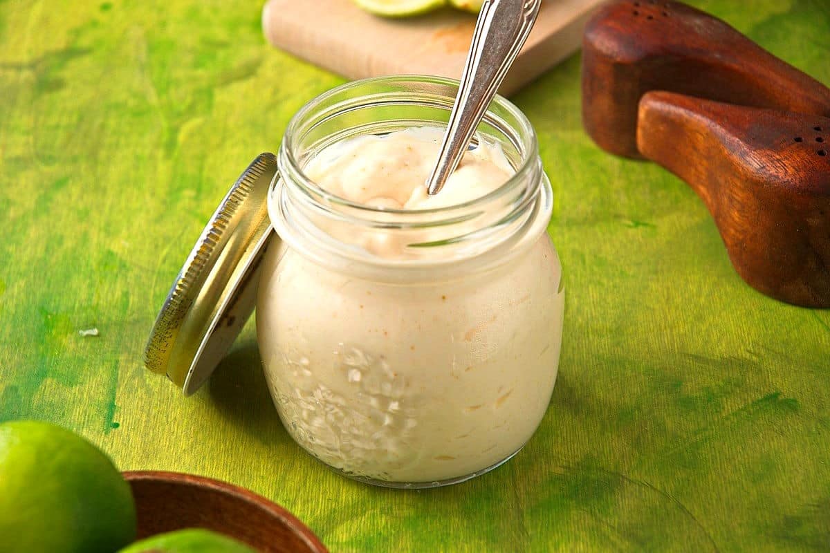 Creamy lime sauce in jar with spoon.