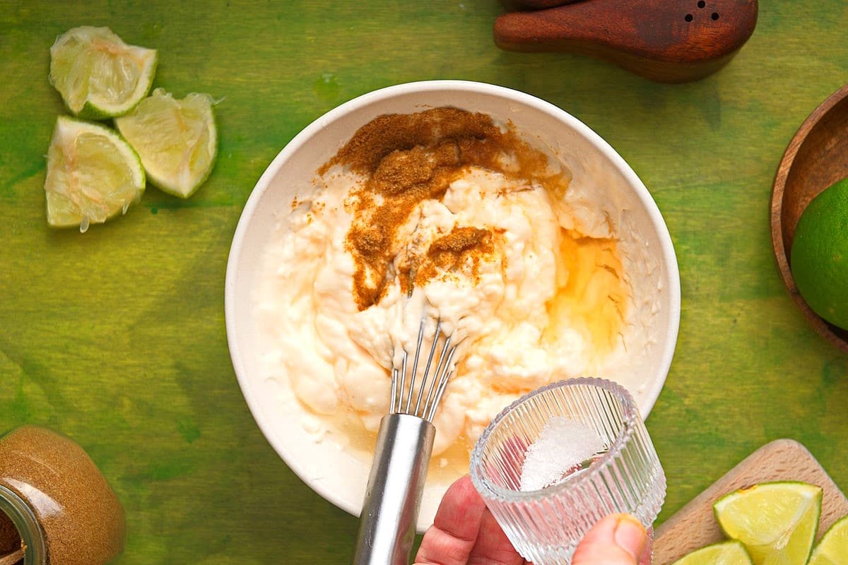 Lime sauce ingredients in bowl with whisk.