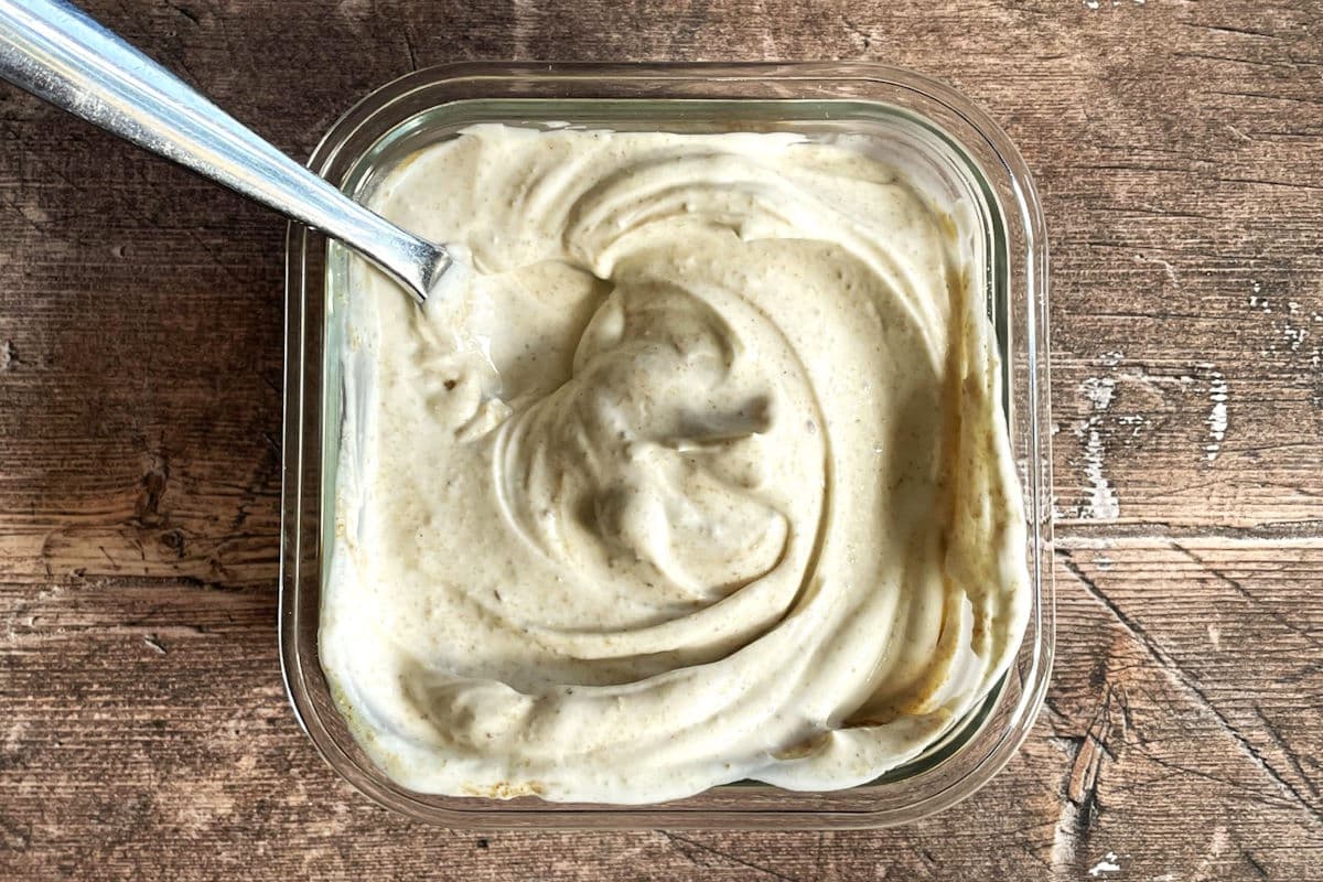 Greek yogurt drizzle in glass dish with spoon.