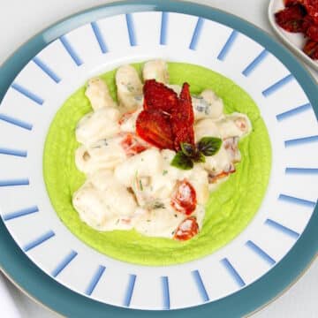 Creamy tomato gnocchi in bowl with pea purée.