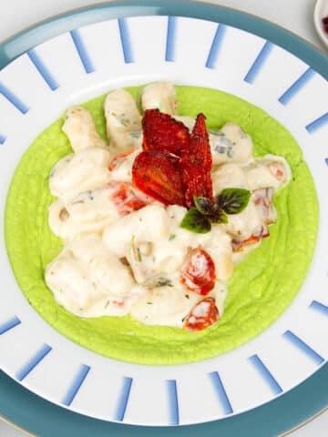 Creamy tomato gnocchi in bowl with pea purée.
