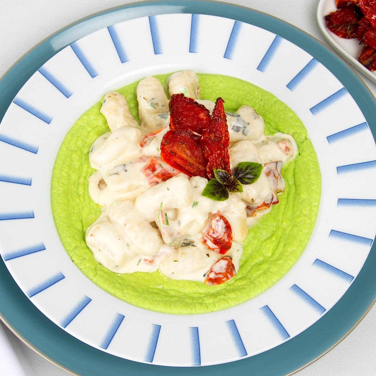 Creamy tomato gnocchi in bowl with pea purée.