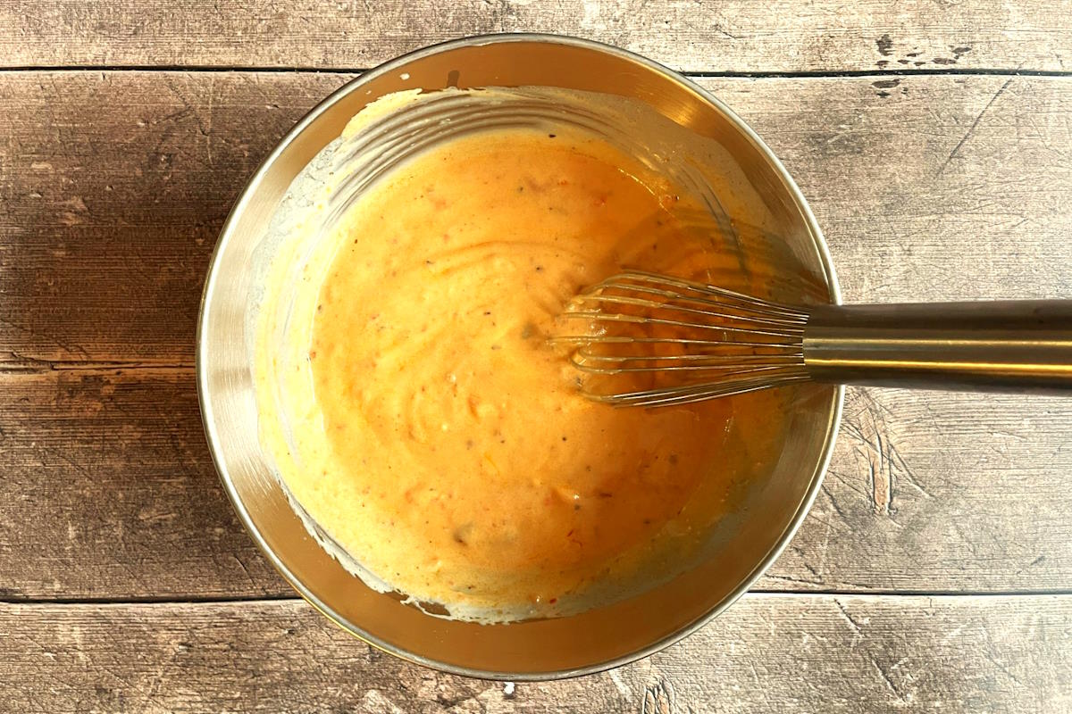 Tomato alfredo sauce in bowl with whisk.