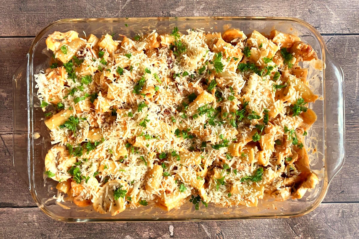 Unbaked tuna macaroni pasta topped with Parmesan cheese in casserole dish.