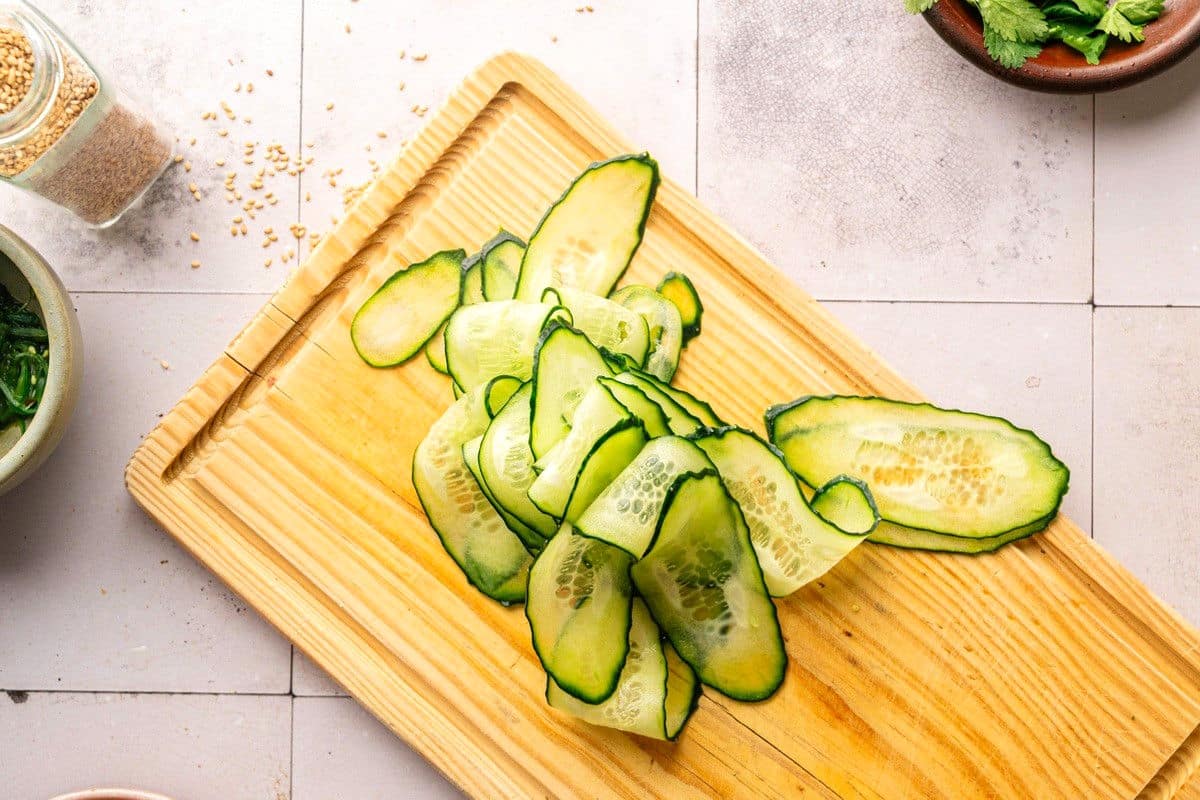 Thinly sliced cucumbers on cutting board.