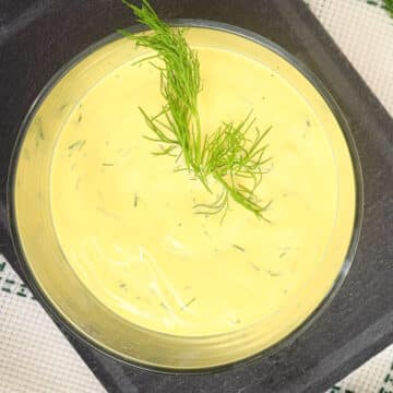 Dill dip in serving bowl with fresh dill on top.