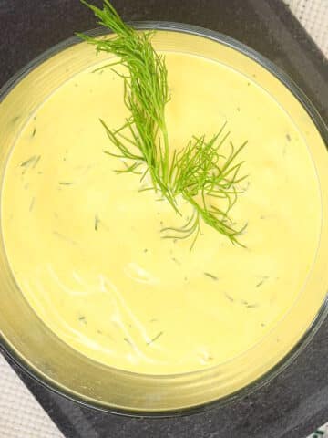 Dill dip in serving bowl with fresh dill on top.
