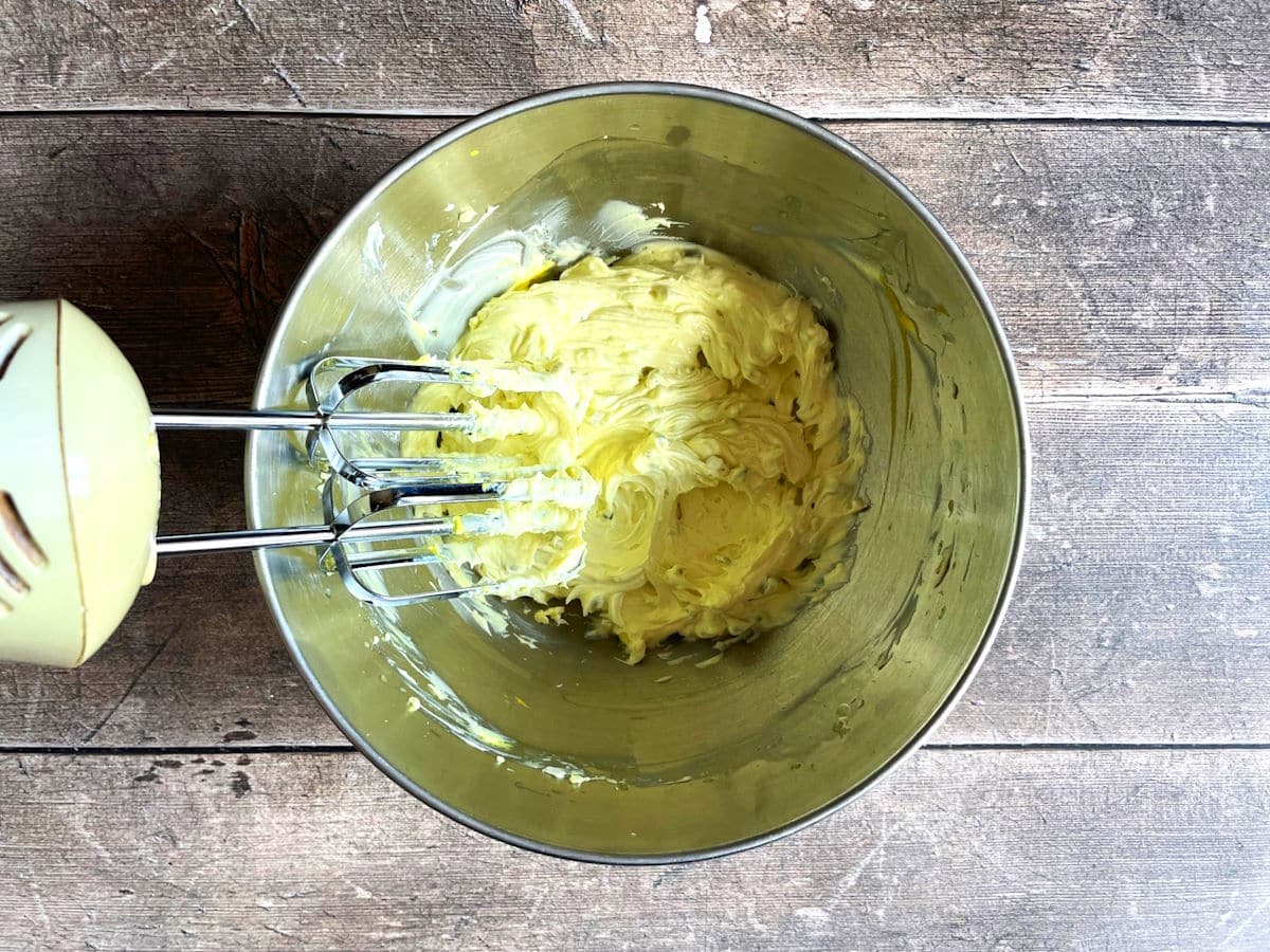 Cream cheese and pickle juice in bowl with electric mixer.