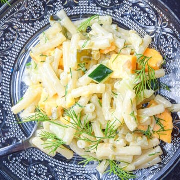 Dill pickle pasta salad on clear, glass plate.