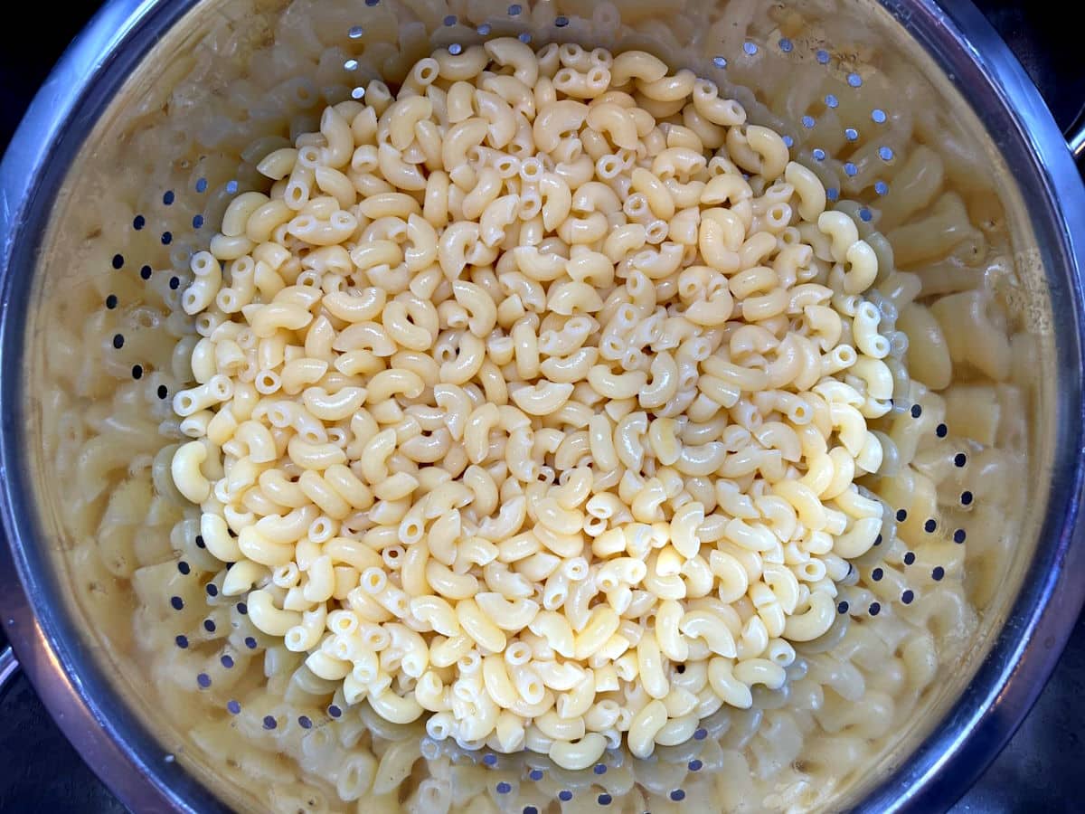 Cooked macaroni in metal colander.