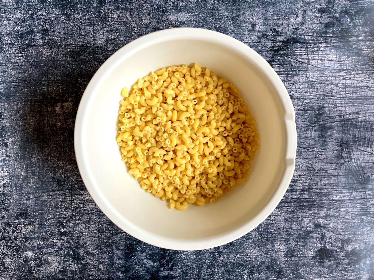 Cooked macaroni pasta in white bowl.