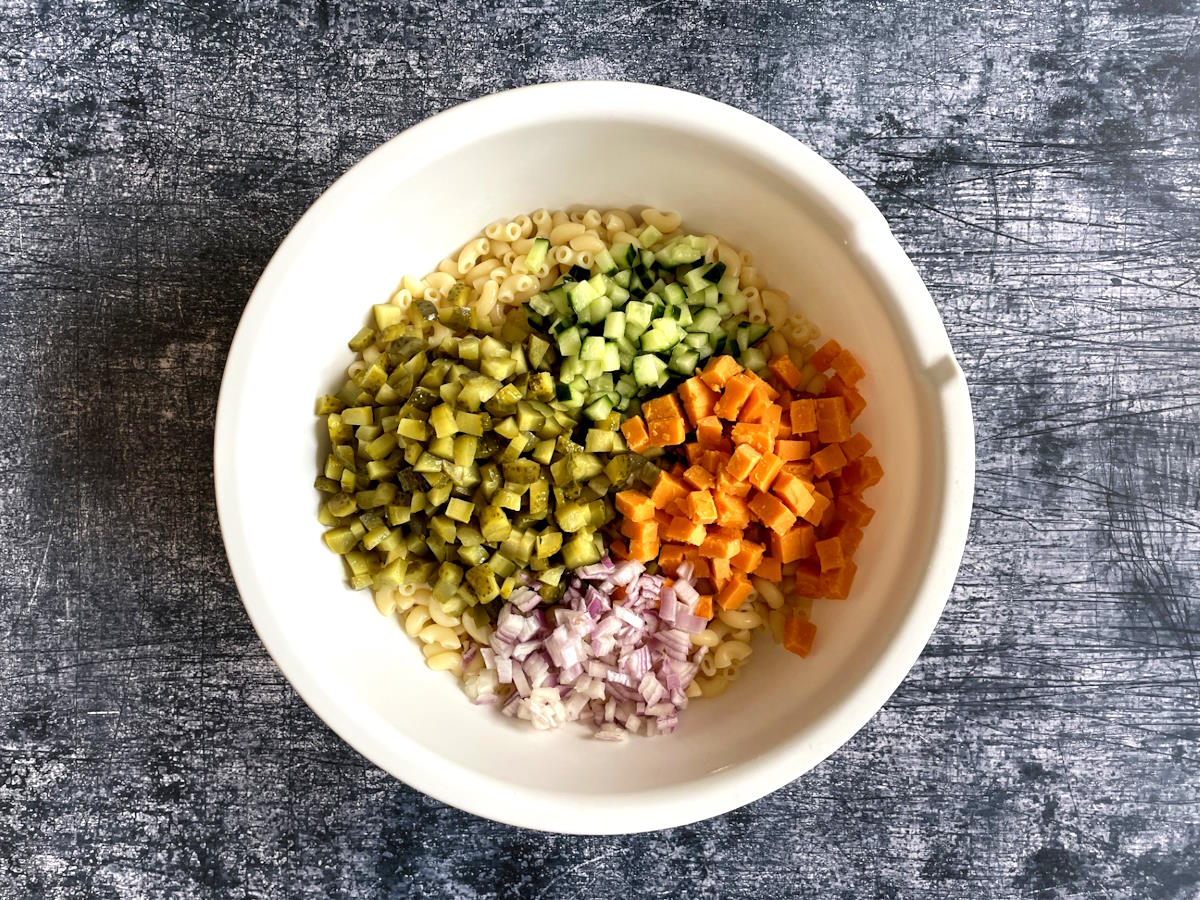 Dill pickle pasta salad ingredients in large bowl.