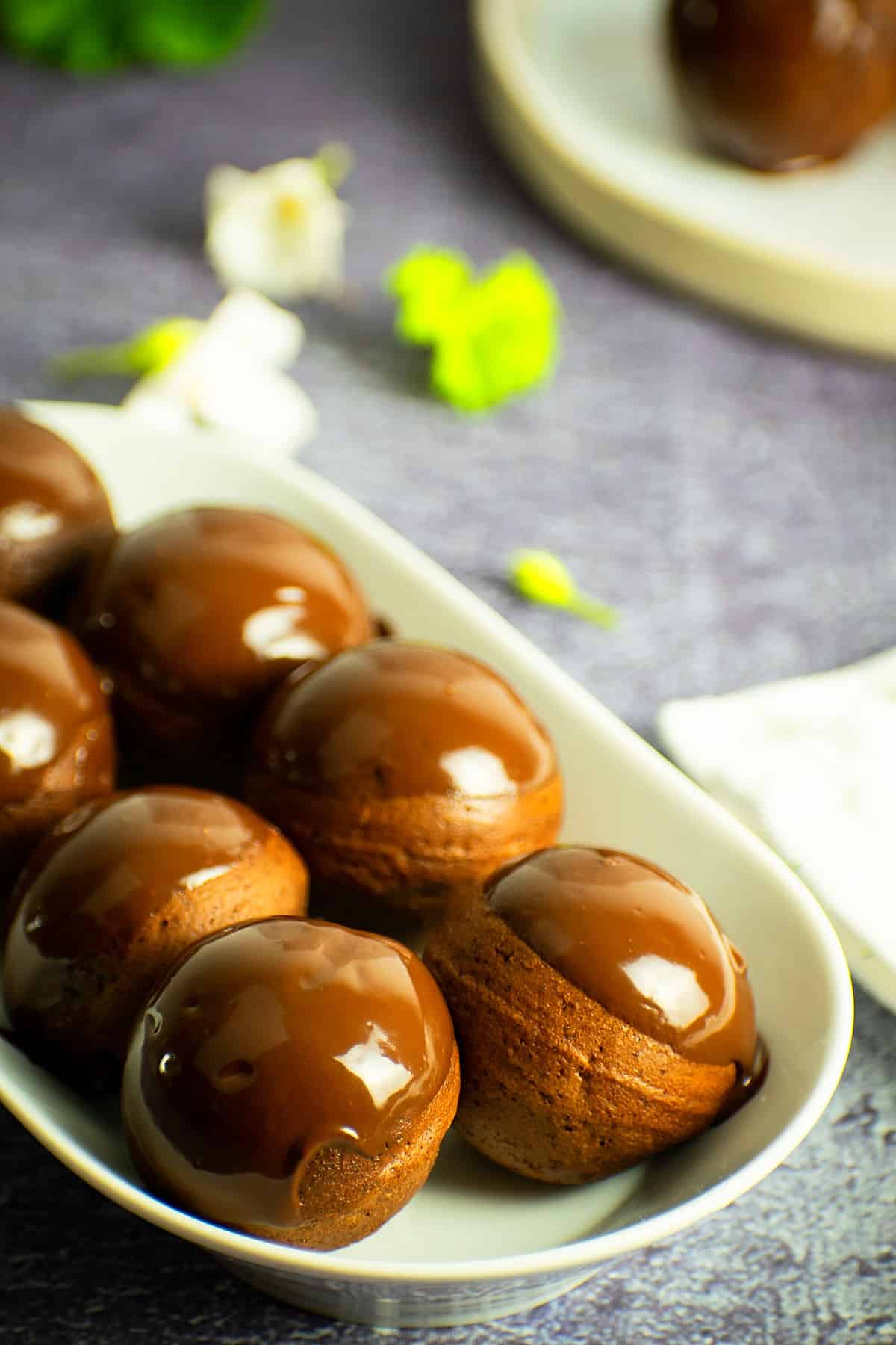 Chocolate covered donut holes in white dish.