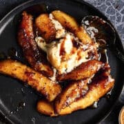 Bananas Foster on black plate with ice cream.