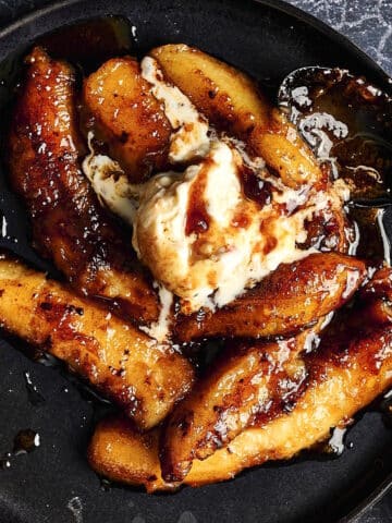 Bananas Foster on black plate with ice cream.