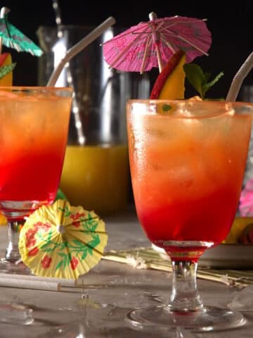 Hawaiian Mai Tais with umbrellas, straws and mango slices.