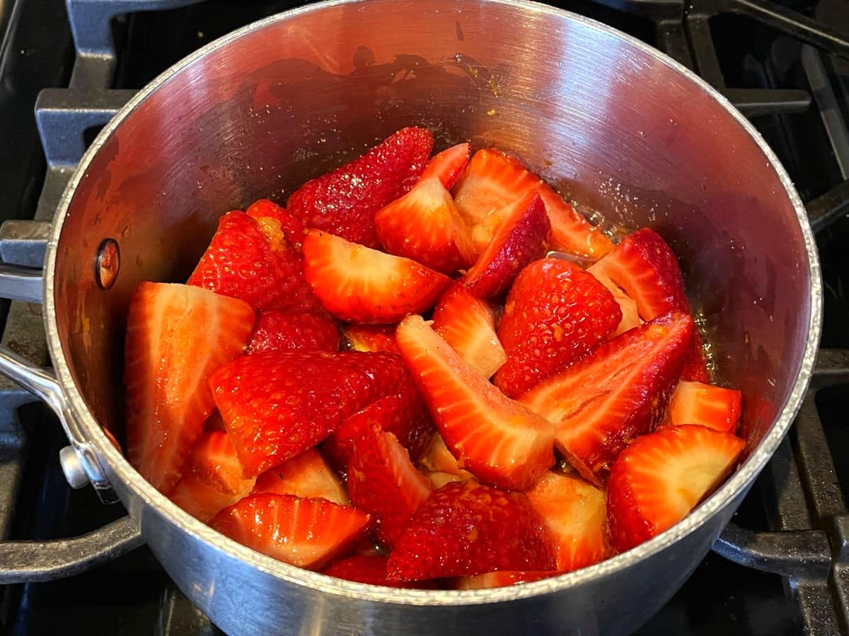 Strawberry compote mixture simmering in saucepan.