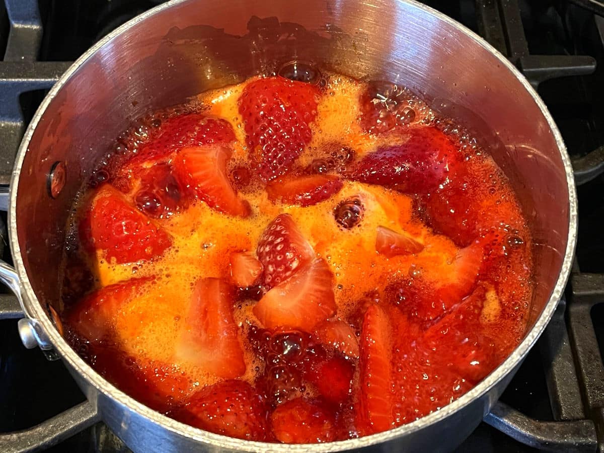 Strawberry compote mixture in saucepan with cornstarch.
